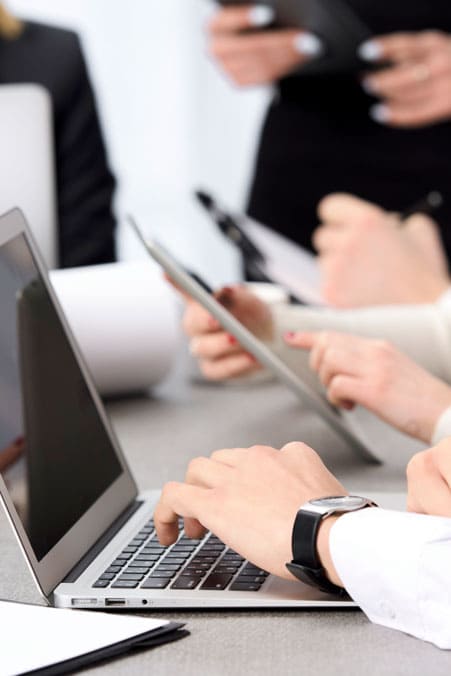 Equipo de profesionales trabajando con portátiles y tablets sin interrupciones de conexión en un entorno empresarial.